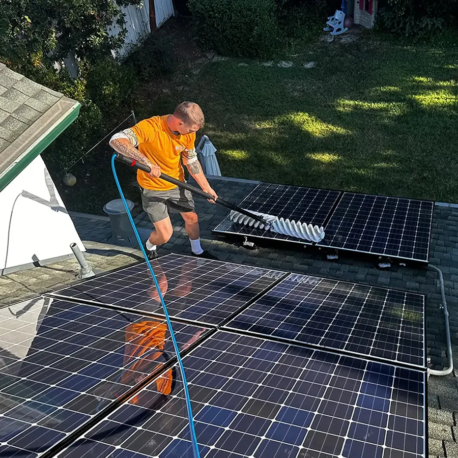 Solar panel technician cleaning an array of residential solar panels from above