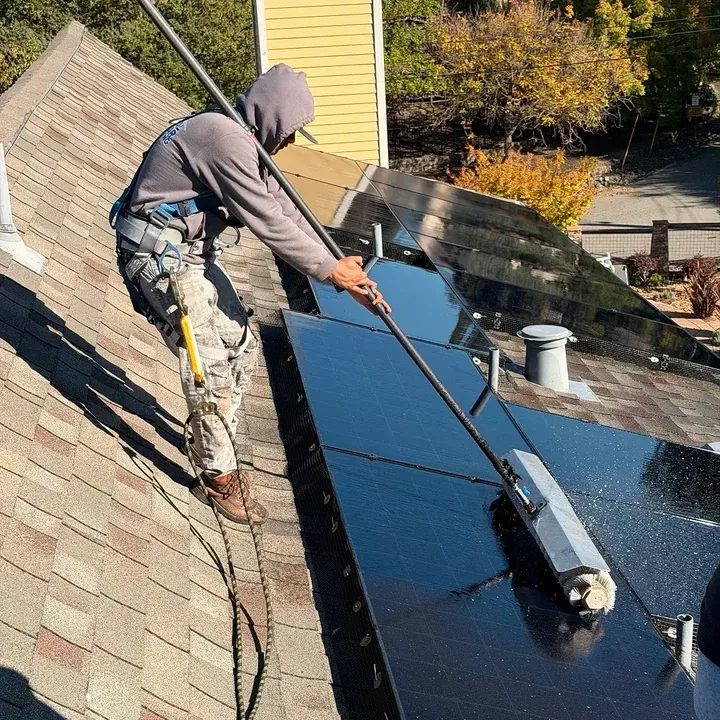 Solar panel cleaning technician working on a residential rooftop